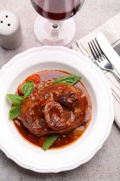 Photo of Traditional ossobuco dish with beef steak served on grey table, flat lay