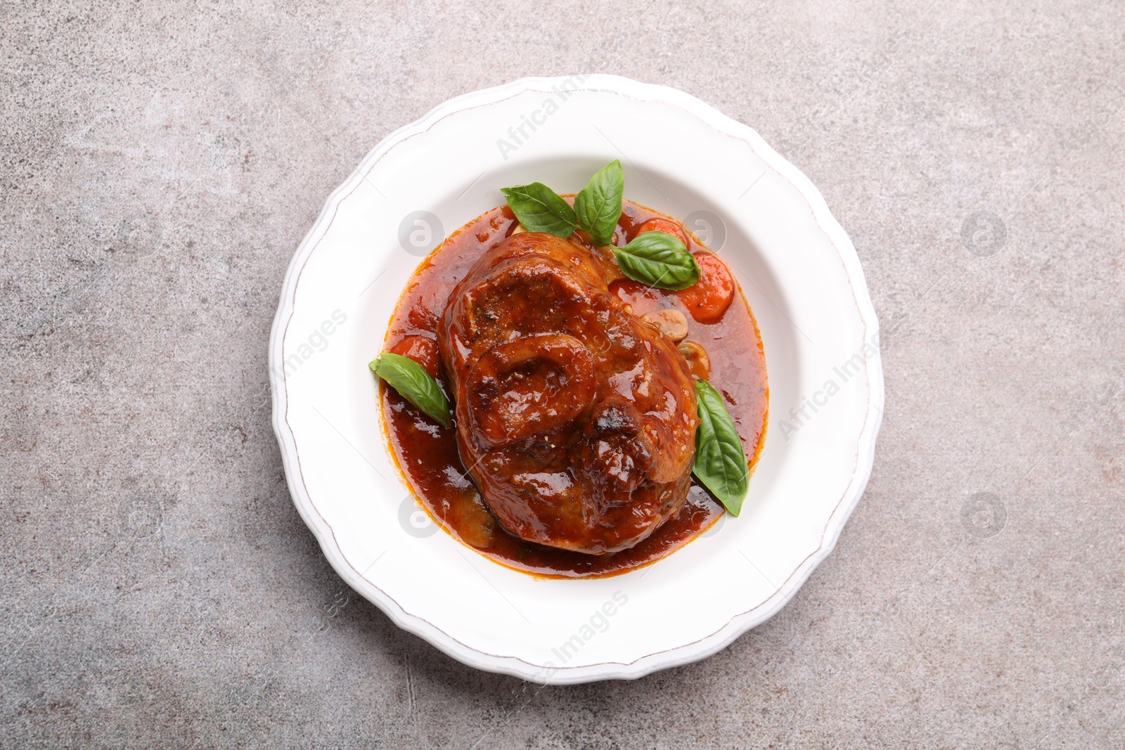 Traditional ossobuco dish with beef steak and sauce on grey table, top view. Photo of Traditional ossobuco dish with beef steak and sauce on grey table, top view.