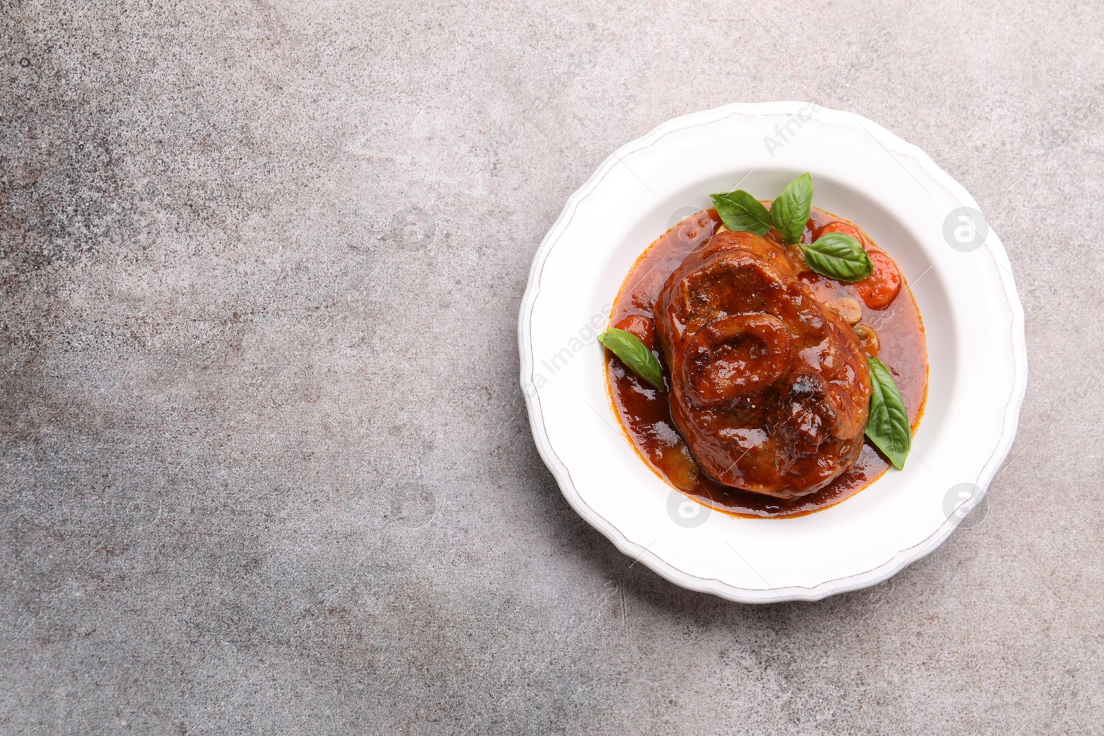 Traditional ossobuco dish with beef steak and sauce on grey table, top view. Space for text Photo of Traditional ossobuco dish with beef steak and sauce on grey table, top view. Space for text