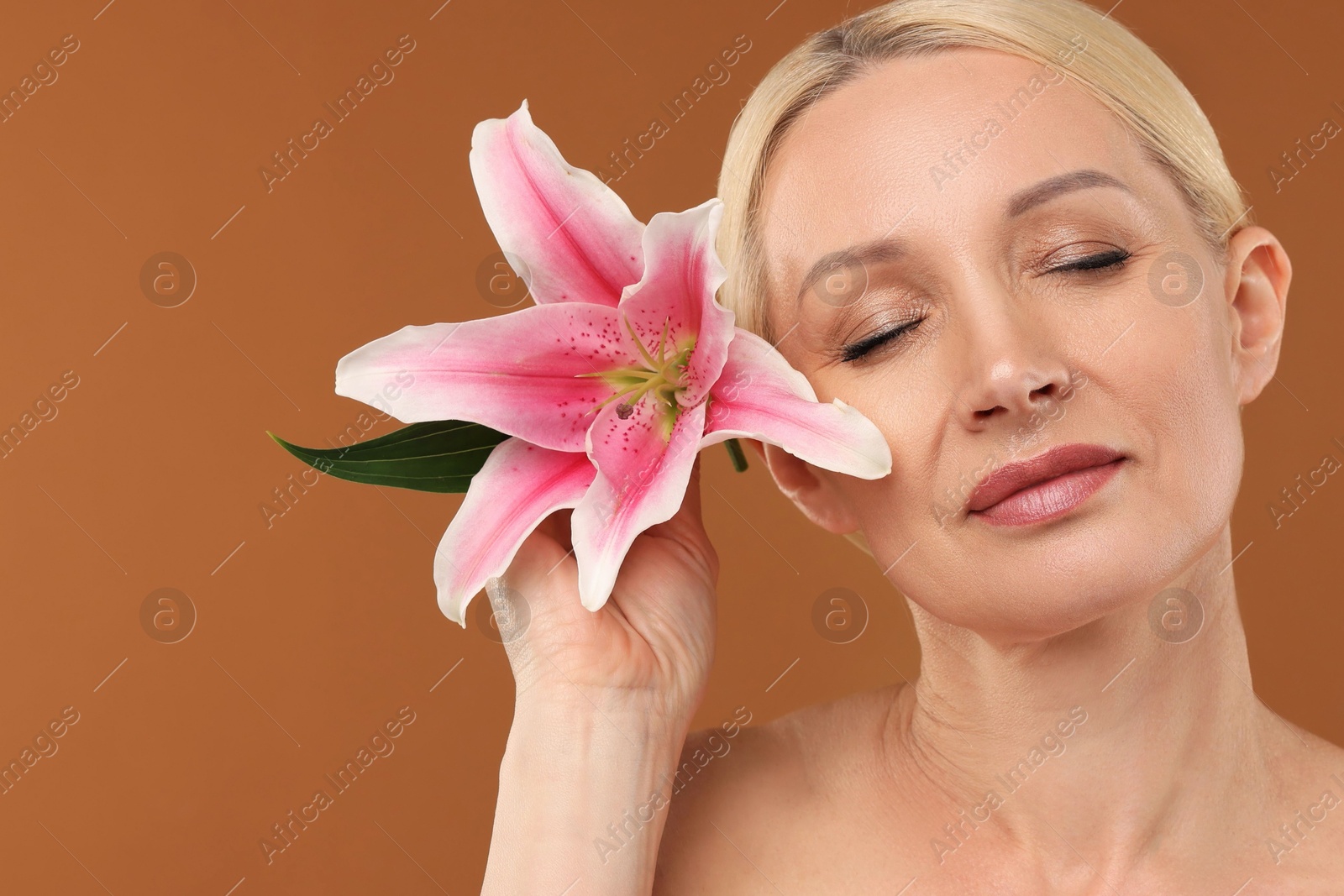 Beautiful woman with lily flower on brown background, closeup Photo of Beautiful woman with lily flower on brown background, closeup