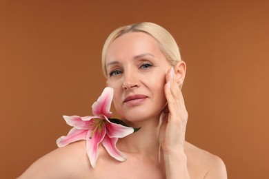 Photo of Beautiful woman with lily flower on brown background