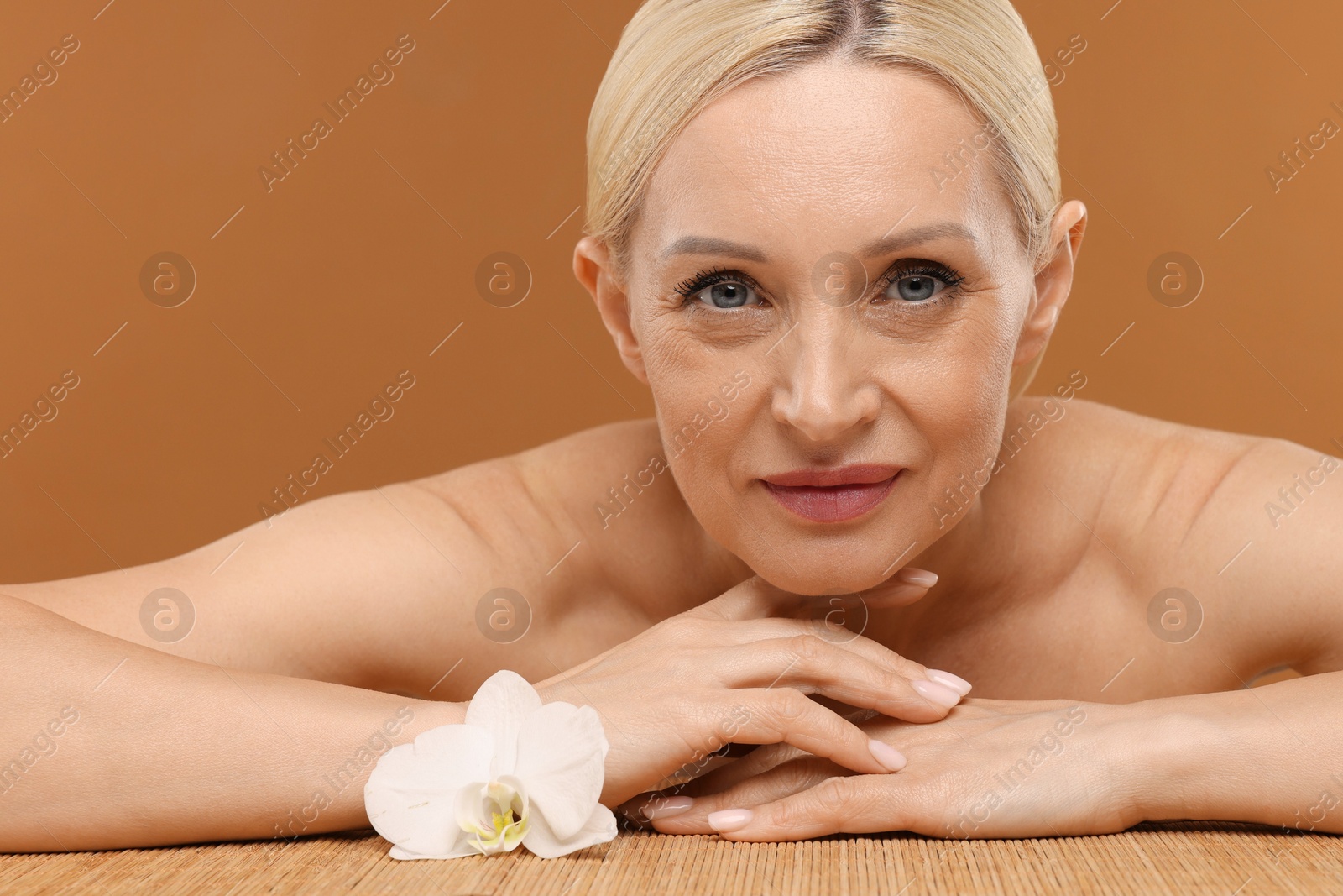 Beautiful woman with orchid flower on brown background, closeup Photo of Beautiful woman with orchid flower on brown background, closeup