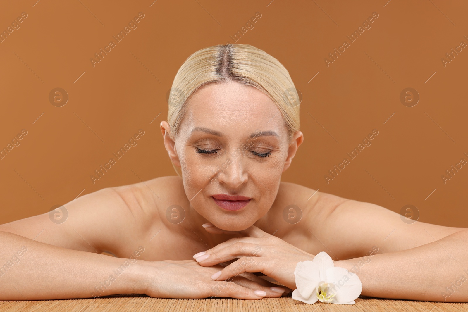 Beautiful woman with orchid flower on brown background Photo of Beautiful woman with orchid flower on brown background