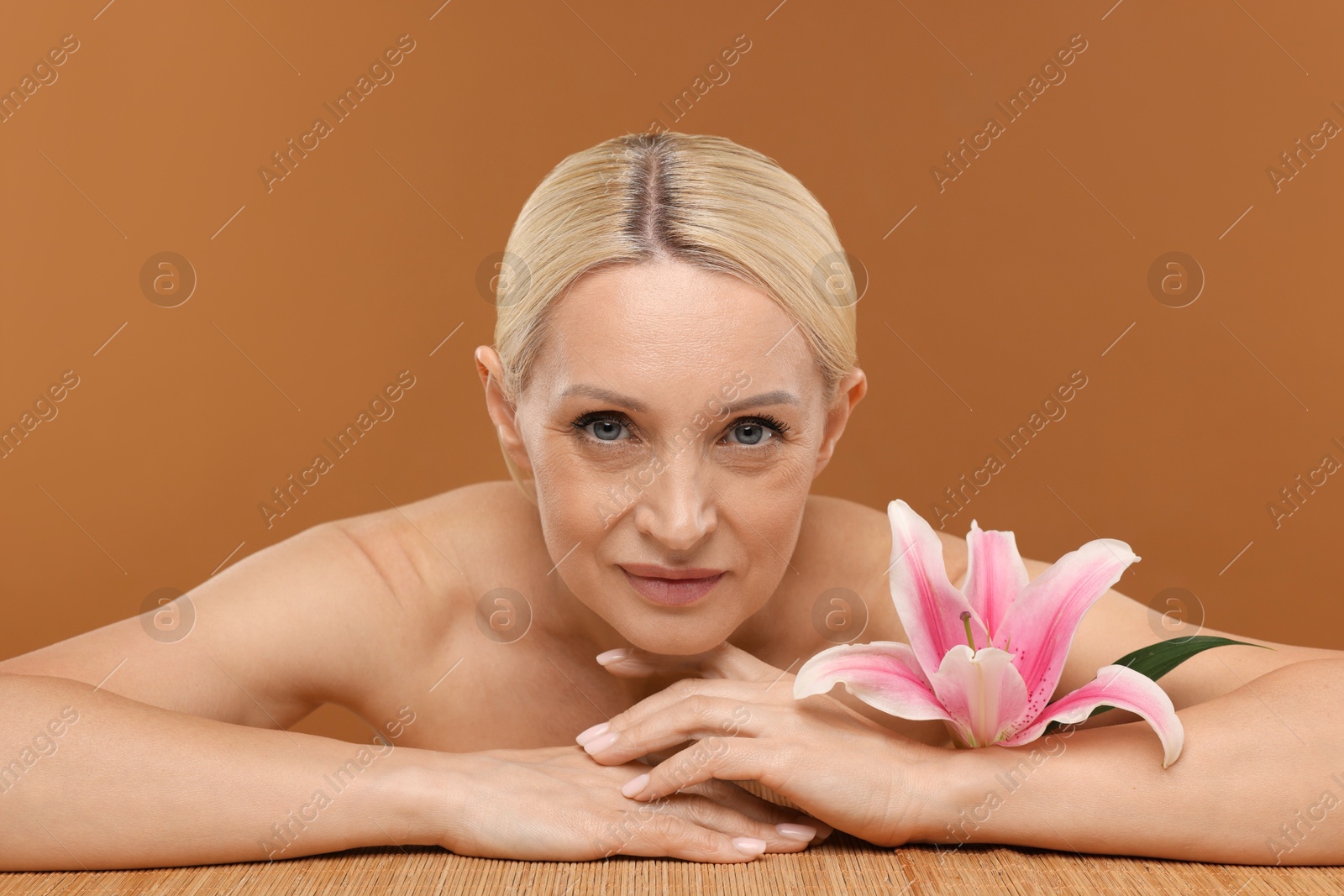 Beautiful woman with lily flower on brown background Photo of Beautiful woman with lily flower on brown background