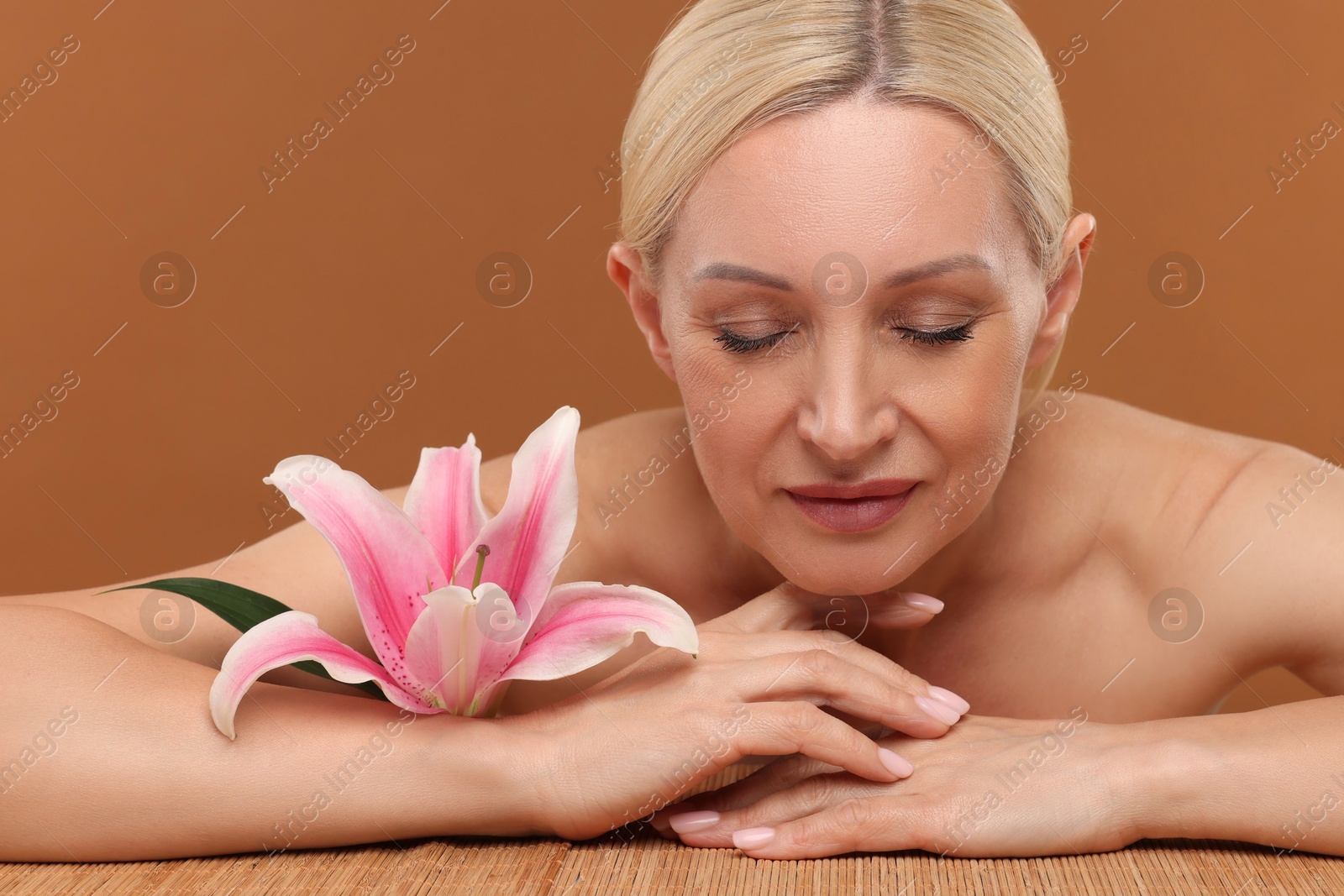 Beautiful woman with lily flower on brown background, closeup Photo of Beautiful woman with lily flower on brown background, closeup