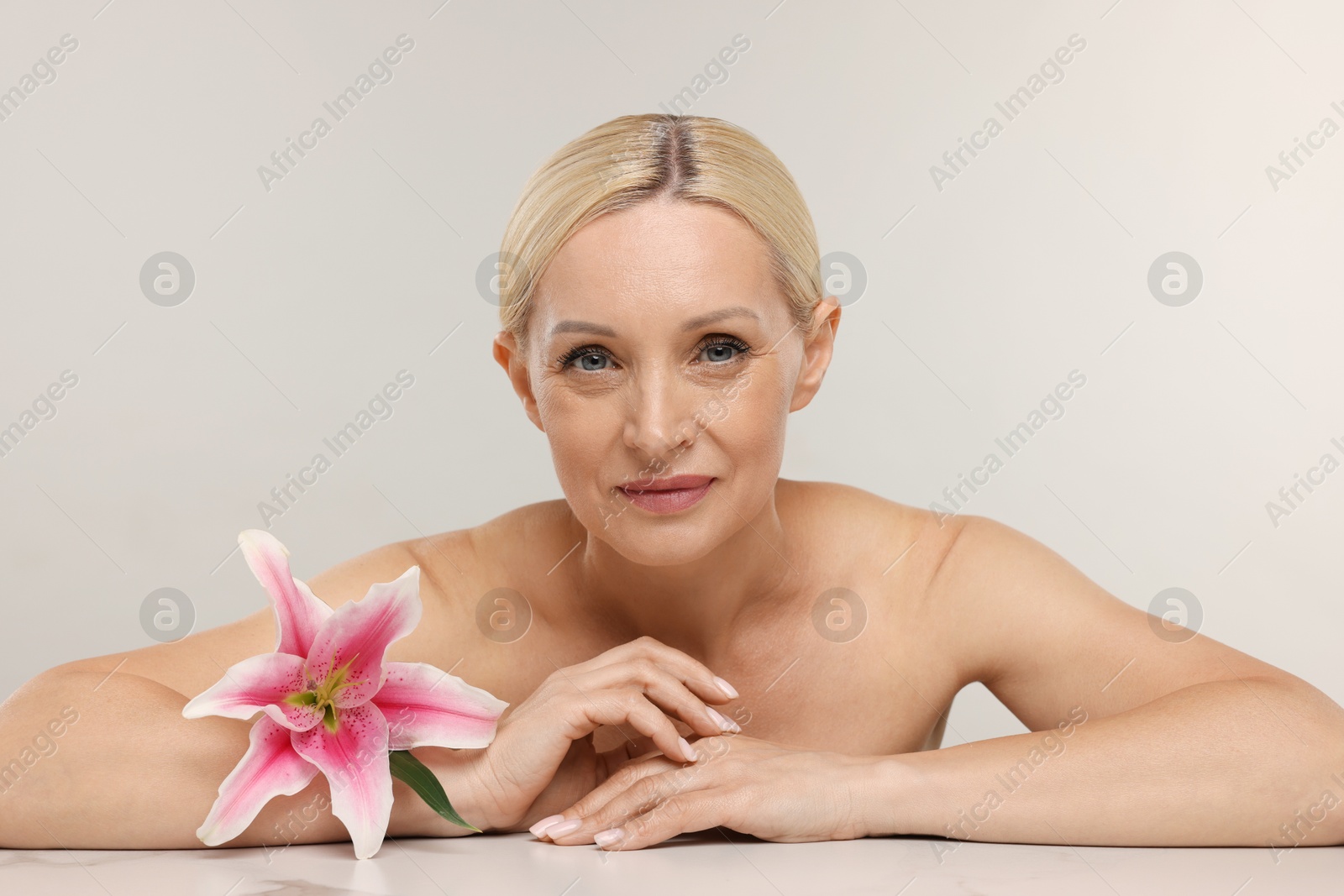 Beautiful woman with lily flower on light background Photo of Beautiful woman with lily flower on light background