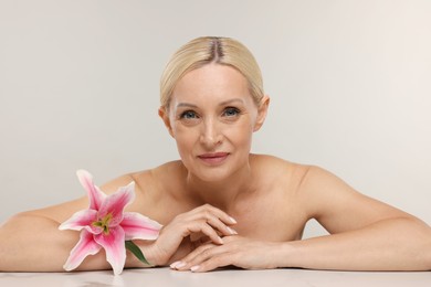 Photo of Beautiful woman with lily flower on light background