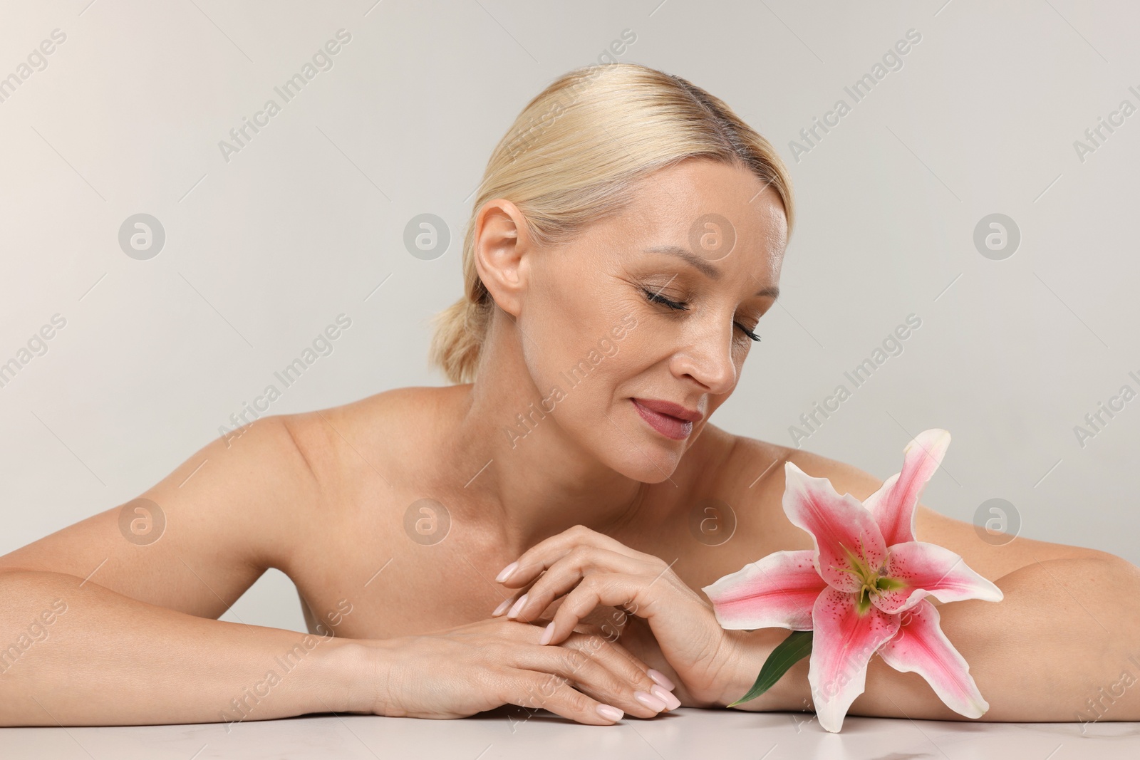 Beautiful woman with lily flower on light background Photo of Beautiful woman with lily flower on light background