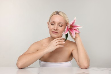 Photo of Beautiful woman with lily flower on light background