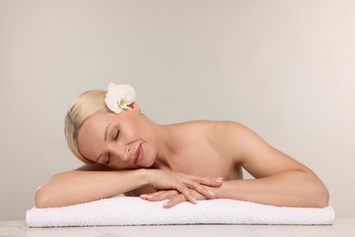 Photo of Beautiful woman with orchid flower and towel on light background. Space for text