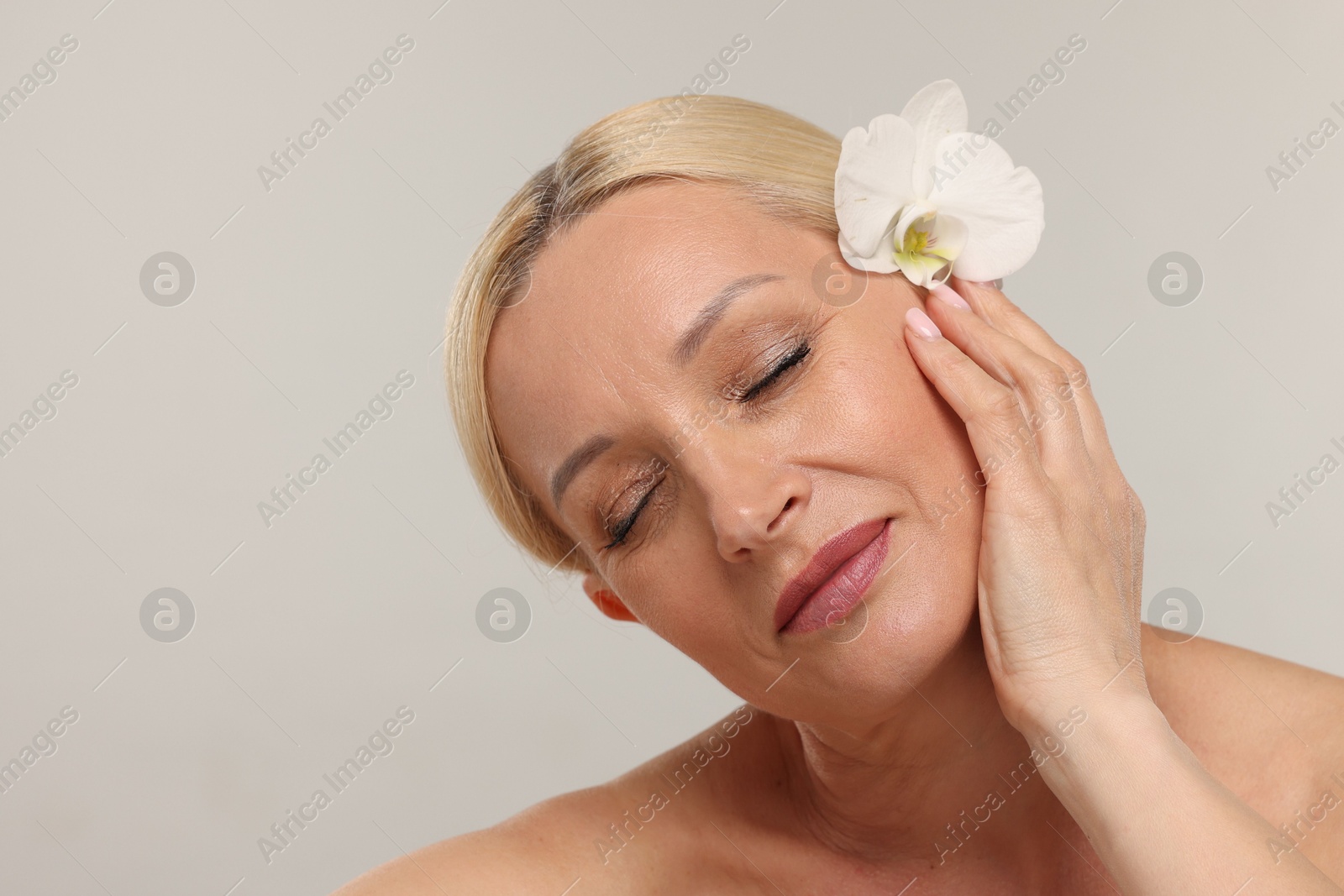 Beautiful woman with orchid flower on light background, closeup Photo of Beautiful woman with orchid flower on light background, closeup