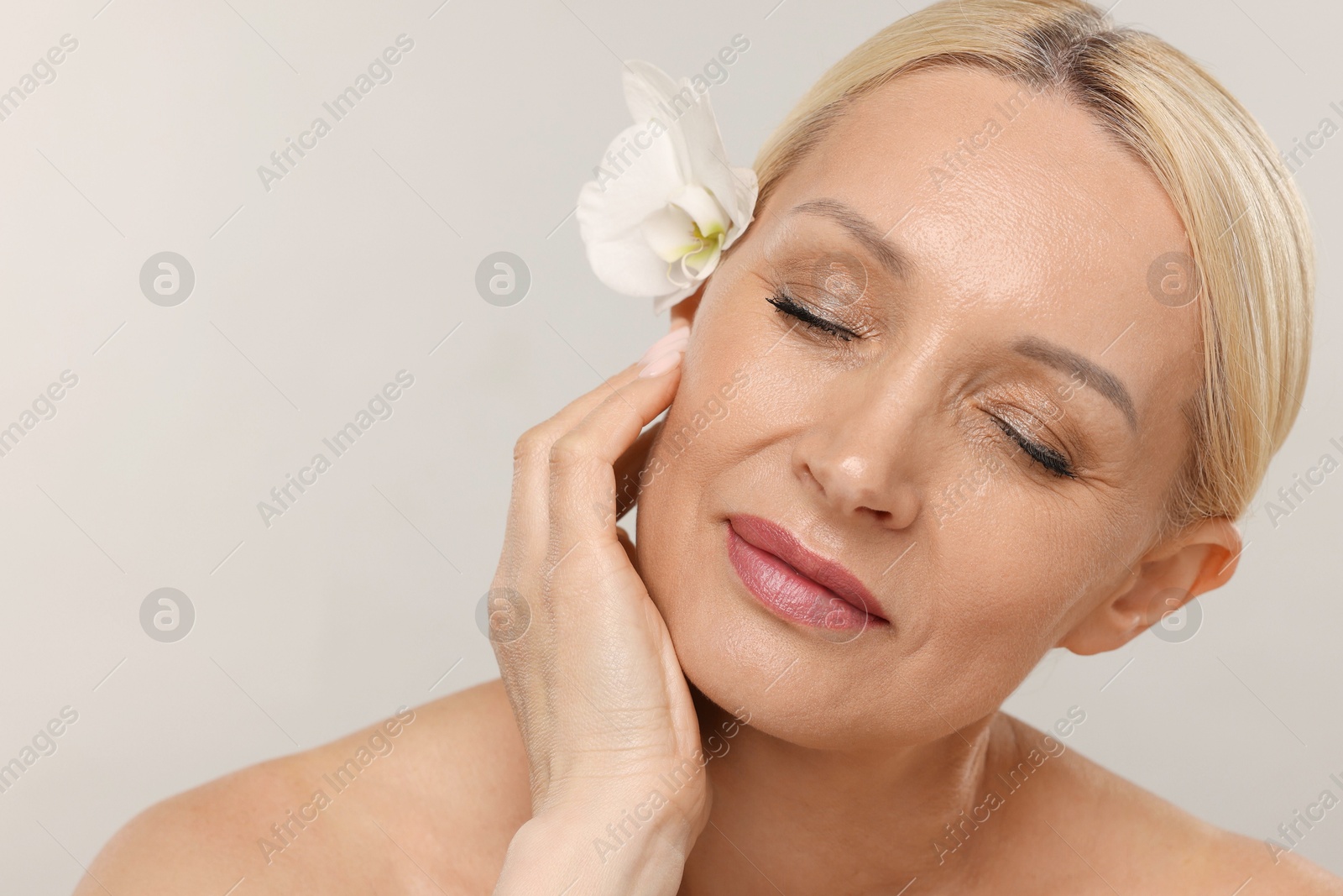 Beautiful woman with orchid flower on light background, closeup. Space for text Photo of Beautiful woman with orchid flower on light background, closeup. Space for text