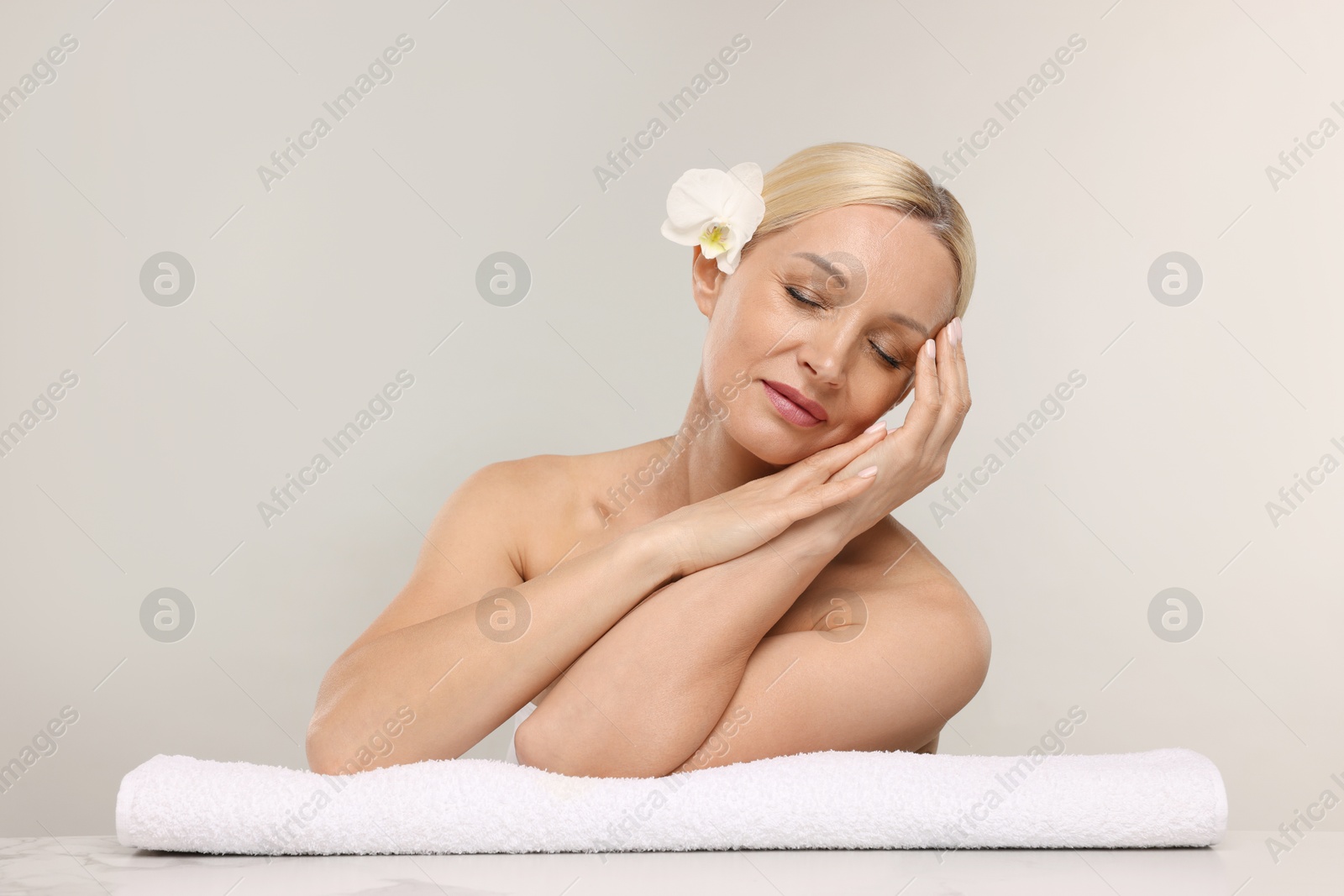 Beautiful woman with orchid flower and towel on light background Photo of Beautiful woman with orchid flower and towel on light background