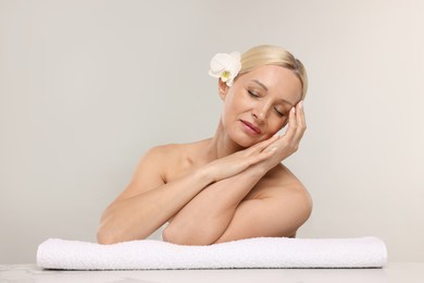 Photo of Beautiful woman with orchid flower and towel on light background