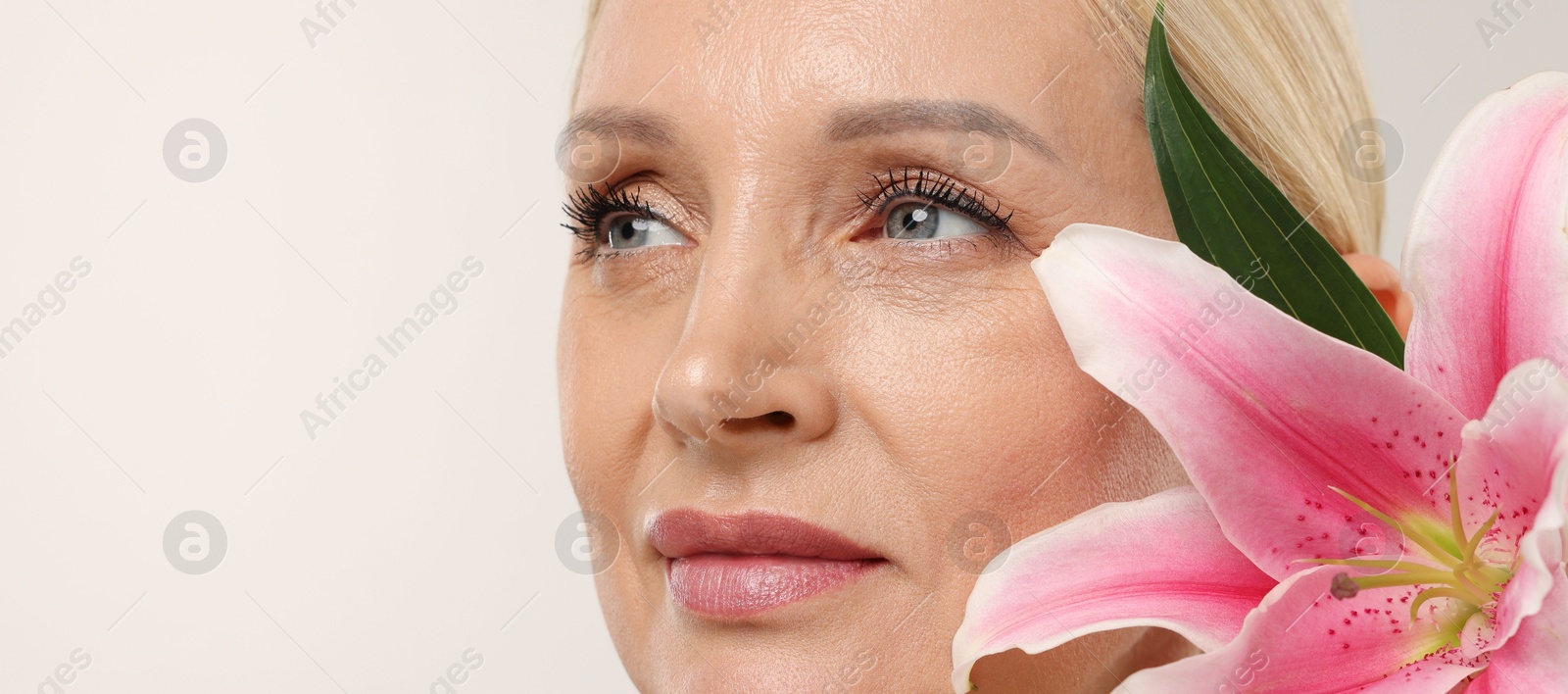 Beautiful woman with lily flower on light background, closeup. Space for text Photo of Beautiful woman with lily flower on light background, closeup. Space for text