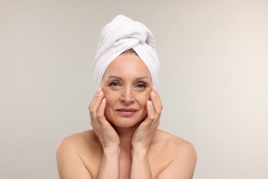 Photo of Beautiful woman with towel wrapped on her head against light background