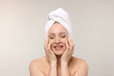 Photo of Beautiful woman with towel wrapped on her head against light background