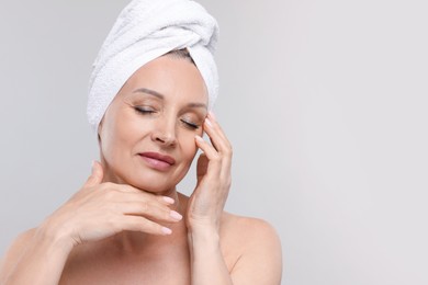 Photo of Beautiful woman with towel wrapped on her head against light background. Space for text