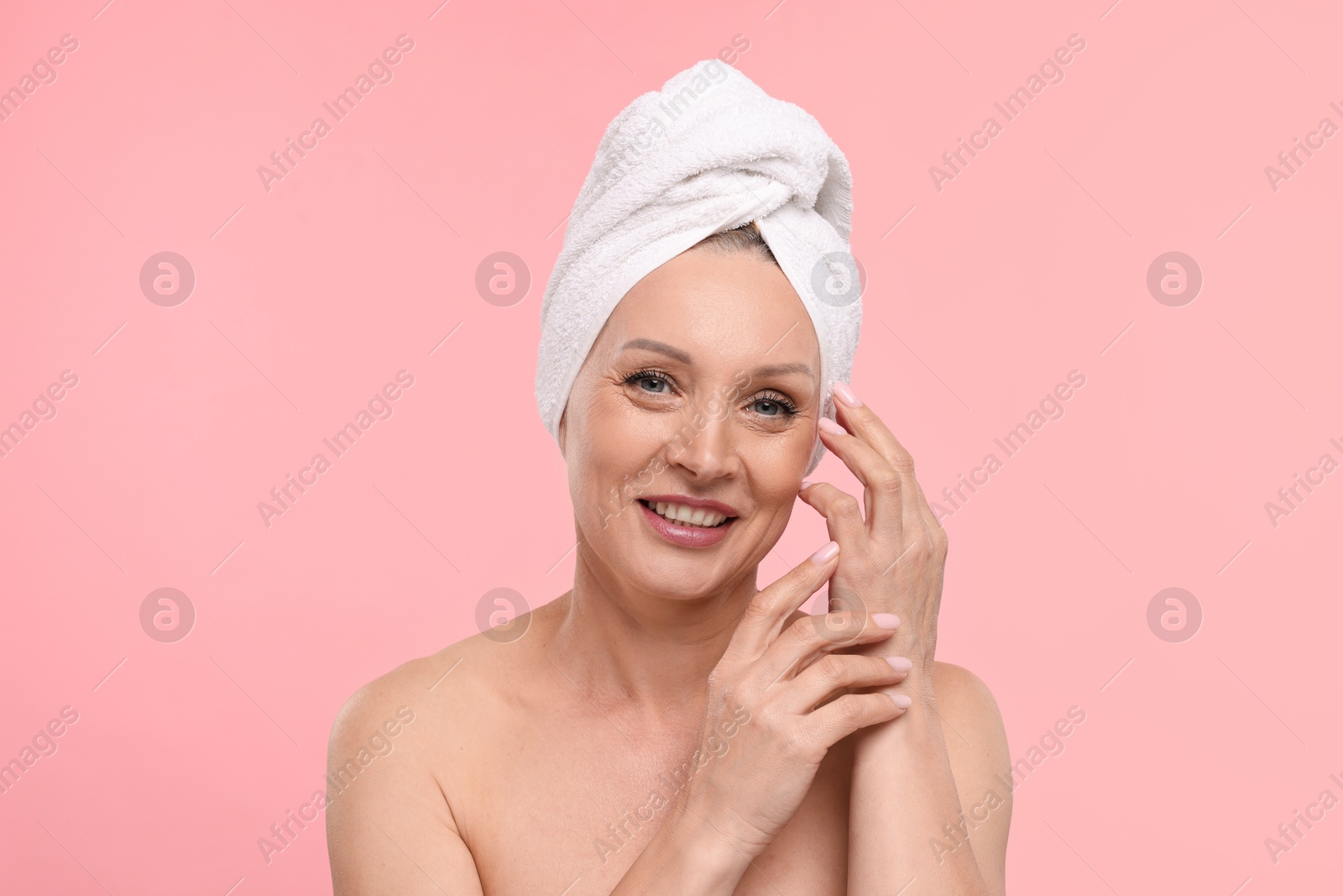 Beautiful woman with towel wrapped on her head against light pink background Photo of Beautiful woman with towel wrapped on her head against light pink background