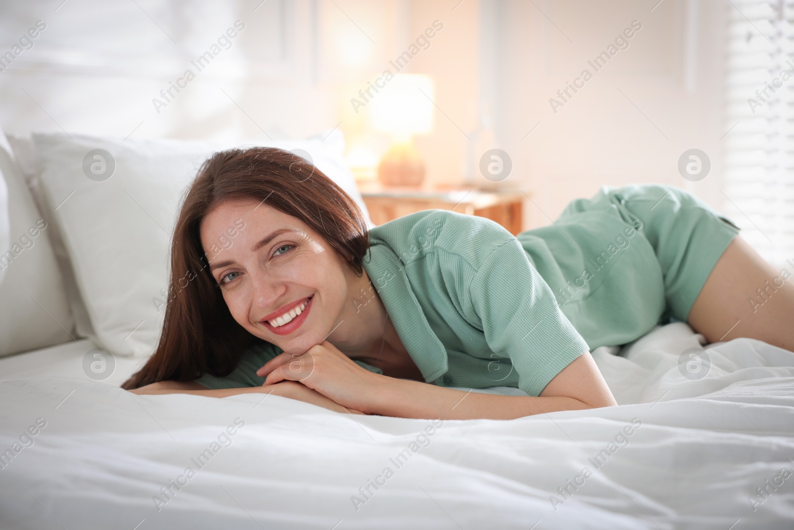 Photo of Woman lying on bed with soft mattress at home