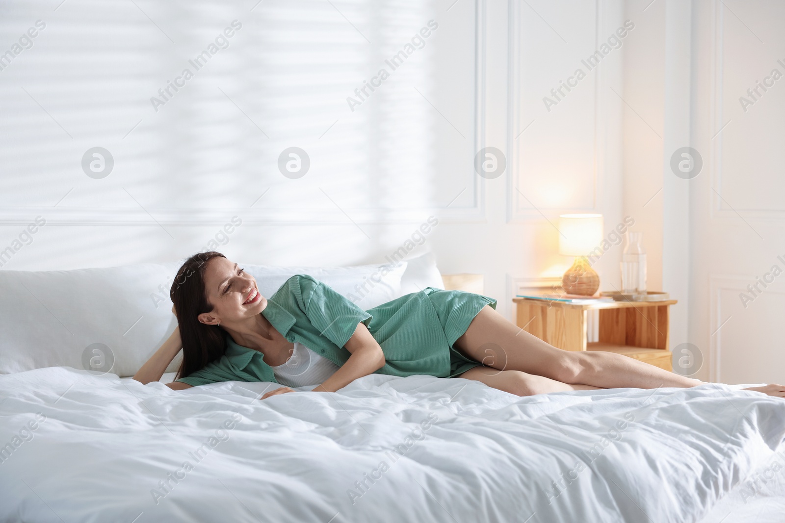 Woman lying on bed with soft mattress at home. Space for text Photo of Woman lying on bed with soft mattress at home. Space for text