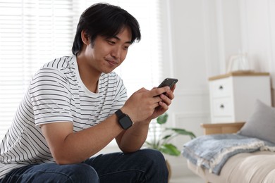 Photo of Handsome Asian man with smartphone at home