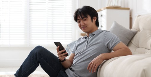 Photo of Handsome Asian man with smartphone at home