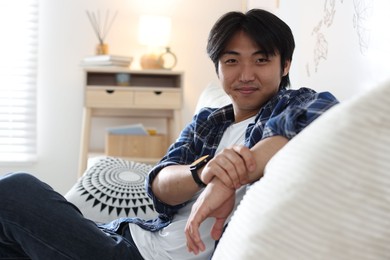 Photo of Handsome Asian man sitting on sofa at home