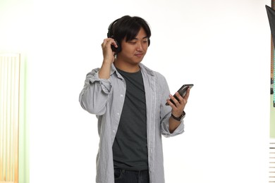 Photo of Handsome Asian man in headphones with smartphone on white background