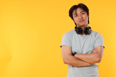 Photo of Portrait of handsome Asian man with headphones on yellow background. Space for text