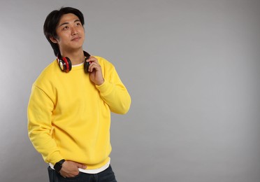 Photo of Handsome Asian man with headphones on grey background. Space for text