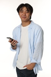 Photo of Portrait of handsome Asian man with smartphone on white background