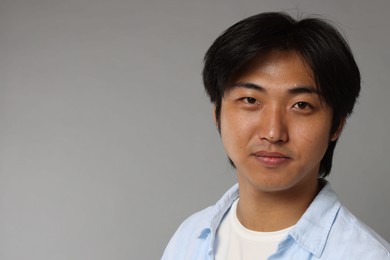 Photo of Portrait of handsome Asian man on grey background. Space for text