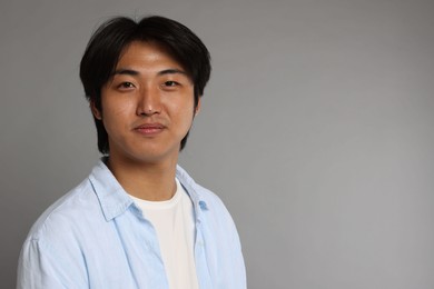 Photo of Portrait of handsome Asian man on grey background. Space for text