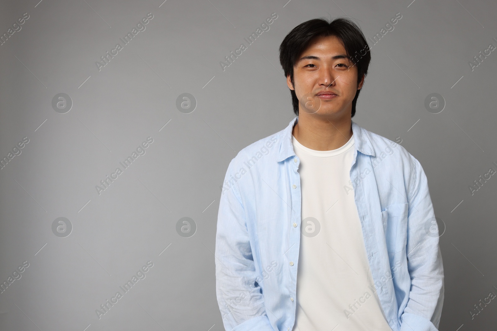 Portrait of handsome Asian man on grey background. Space for text Photo of Portrait of handsome Asian man on grey background. Space for text