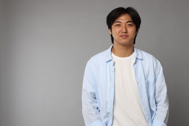Photo of Portrait of handsome Asian man on grey background. Space for text