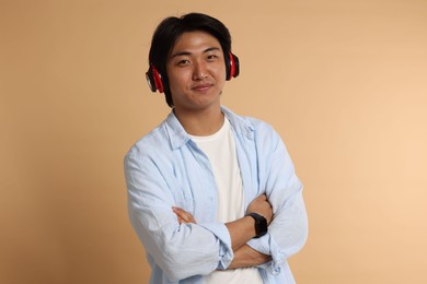 Photo of Handsome Asian man in headphones on beige background
