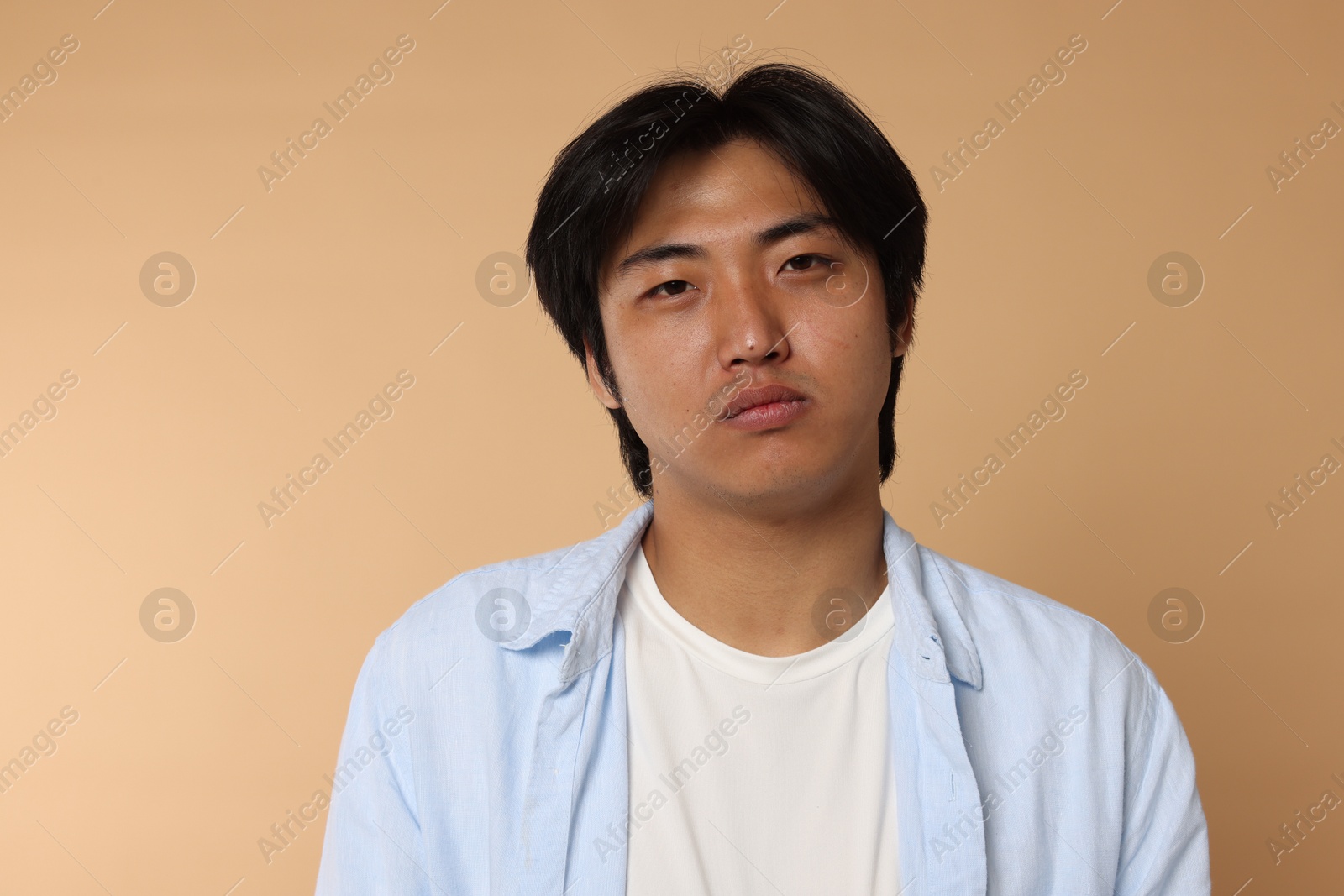 Portrait of handsome Asian man on beige background Photo of Portrait of handsome Asian man on beige background