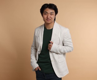 Photo of Portrait of handsome Asian businessman in suit on beige background