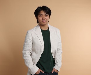Photo of Portrait of handsome Asian businessman in suit on beige background