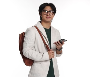 Photo of Portrait of handsome Asian man in glasses with smartphone and backpack on white background