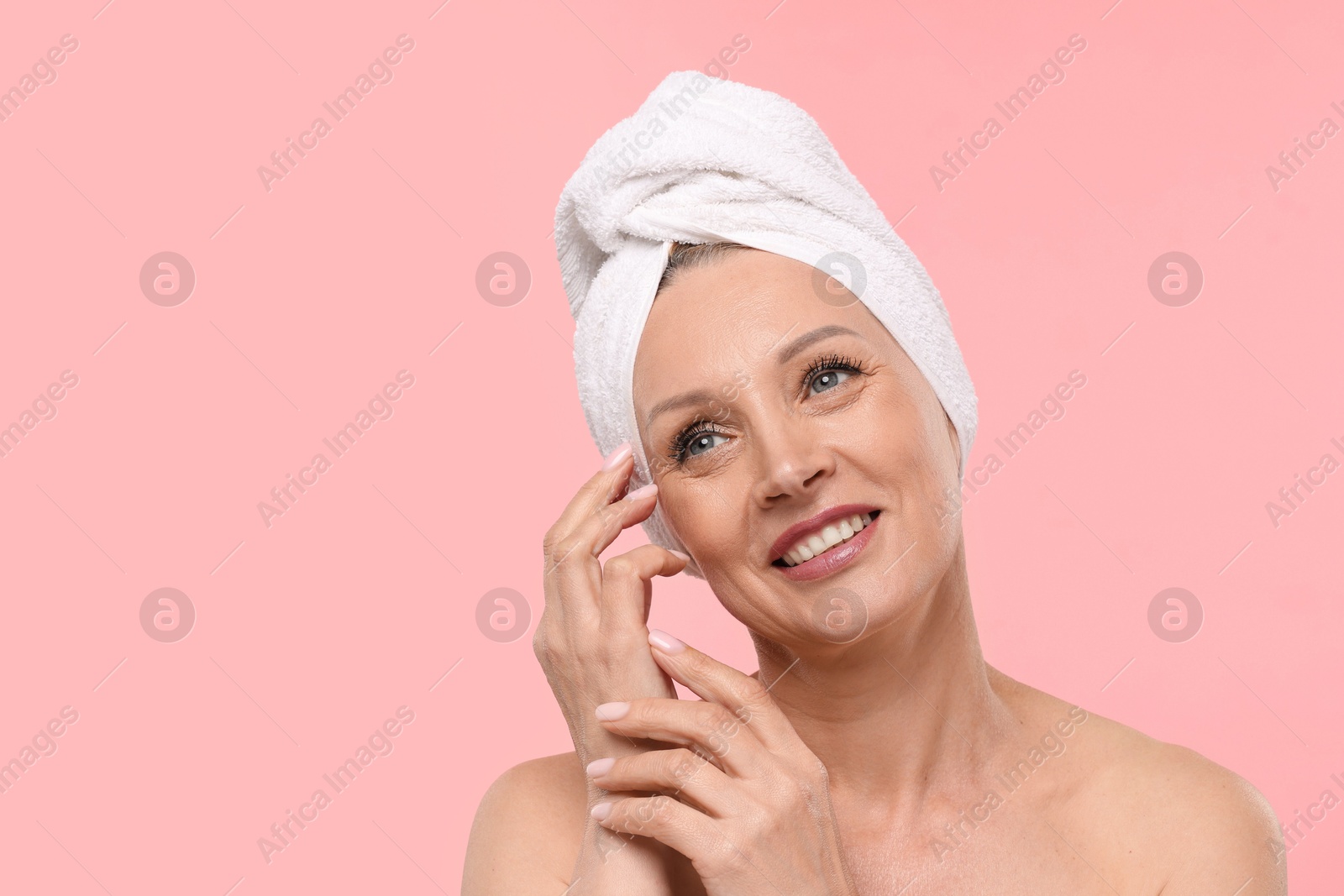 Beautiful woman with towel wrapped on her head against light pink background. Space for text Photo of Beautiful woman with towel wrapped on her head against light pink background. Space for text