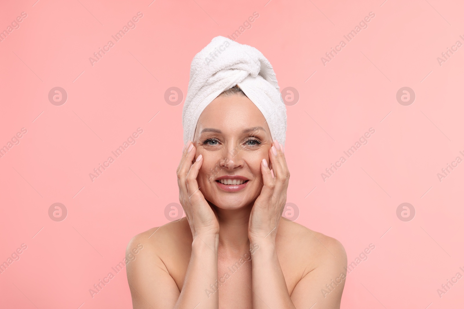 Beautiful woman with towel wrapped on her head against light pink background Photo of Beautiful woman with towel wrapped on her head against light pink background