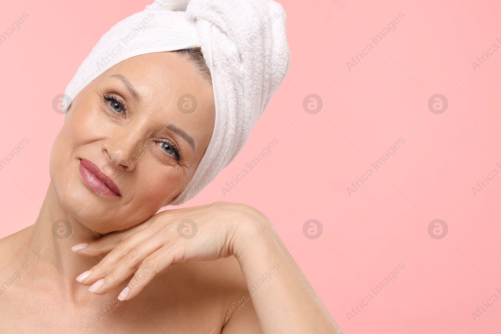 Beautiful woman with towel wrapped on her head against light pink background. Space for text Photo of Beautiful woman with towel wrapped on her head against light pink background. Space for text