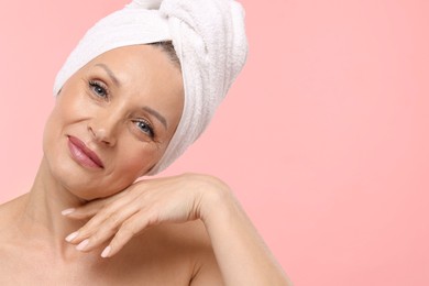Photo of Beautiful woman with towel wrapped on her head against light pink background. Space for text