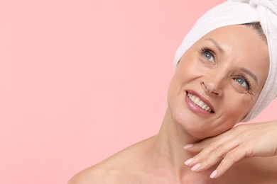 Photo of Beautiful woman with towel wrapped on her head against light pink background. Space for text