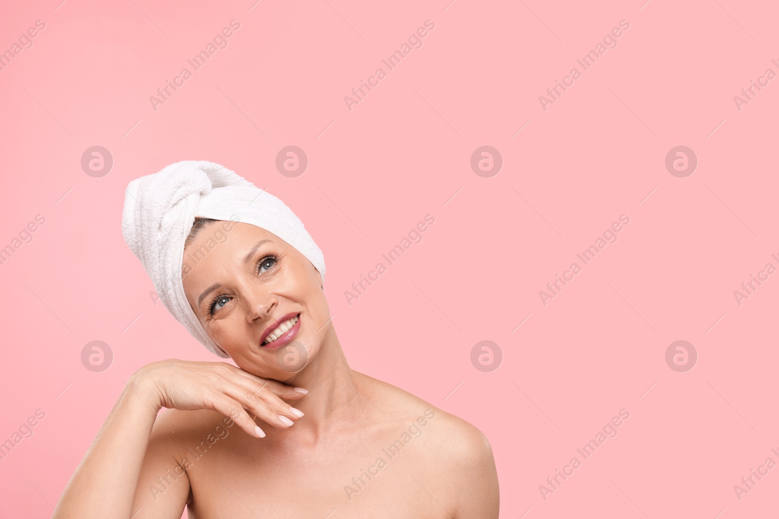 Beautiful woman with towel wrapped on her head against light pink background. Space for text Photo of Beautiful woman with towel wrapped on her head against light pink background. Space for text