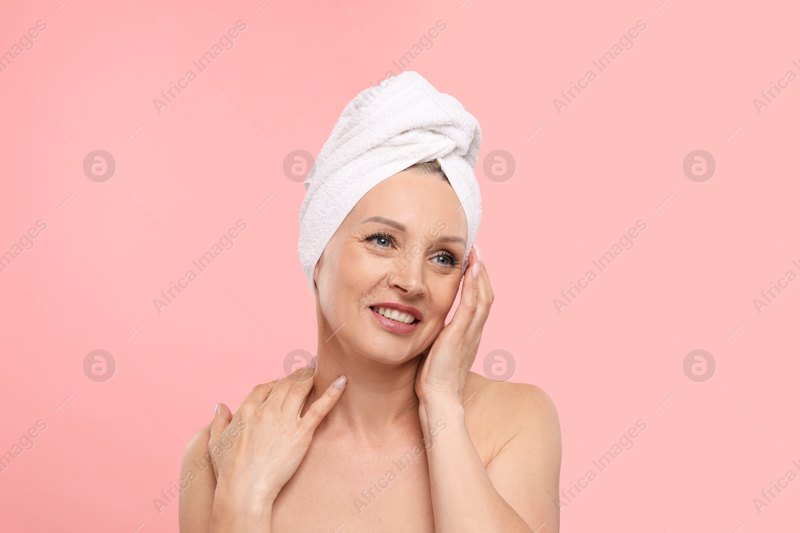 Beautiful woman with towel wrapped on her head against light pink background Photo of Beautiful woman with towel wrapped on her head against light pink background