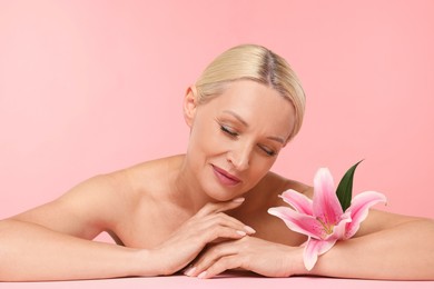 Photo of Beautiful woman with lily flower on light pink background