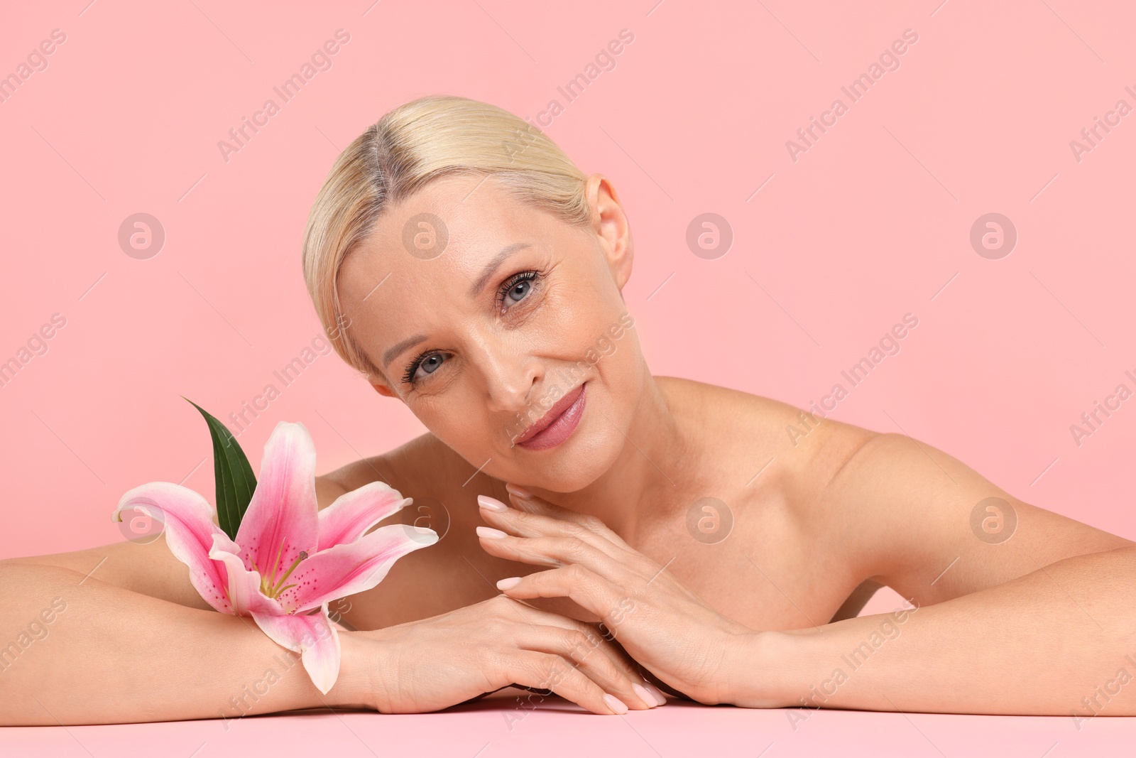 Beautiful woman with lily flower on light pink background Photo of Beautiful woman with lily flower on light pink background